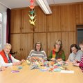 Sechs Frauen am Tisch basteln Faltkraniche.